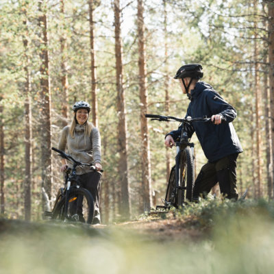Nainen ja mies pyöräilemässä Sallan pyöräreitilla metsässä